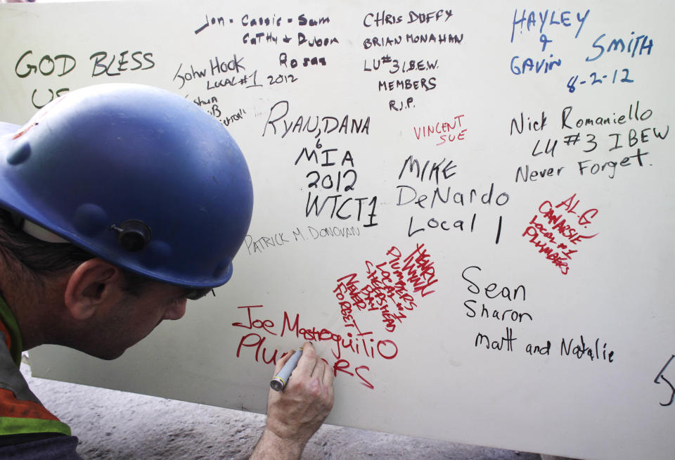 FILE- In this Aug. 2, 2012 file photo, a construction worker signs a ceremonial steel beam at One World Trade Center in New York. The beam was signed by President Barack Obama with the notes: "We remember," ''We rebuild" and "We come back stronger!" during a ceremony at the construction site June 14. The beam, having since adorned with the autographs of workers and police officers at the site, will be sealed into the structure of the tower, which is scheduled for completion in 2014. (AP Photo/Mark Lennihan, File)