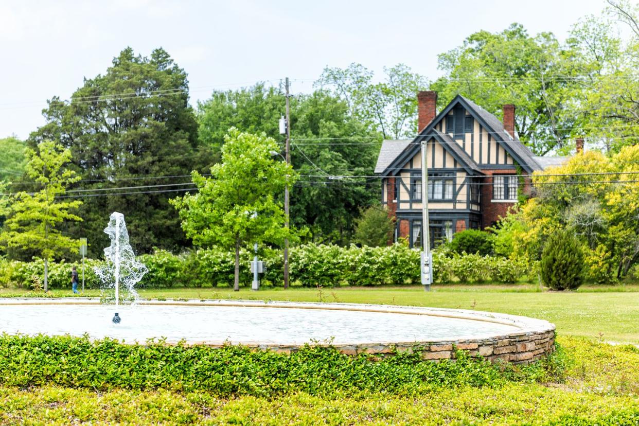 legrande park in montgomery, usa during green spring in alabama capital city during sunny day with water fountain stream spraying up, historic residential house