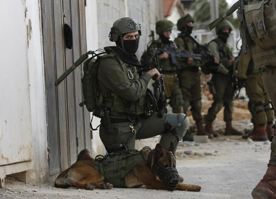 Israeli forces search for a Palestinian gunman in the village of Bruqin near the West Bank town of Salfit, Sunday, March 17, 2019. The Israeli military says a Palestinian killed an Israeli and seriously wounded two others in a West Bank shooting and stabbing spree before fleeing and setting off a massive manhunt. (AP Photo/Majdi Mohammed)