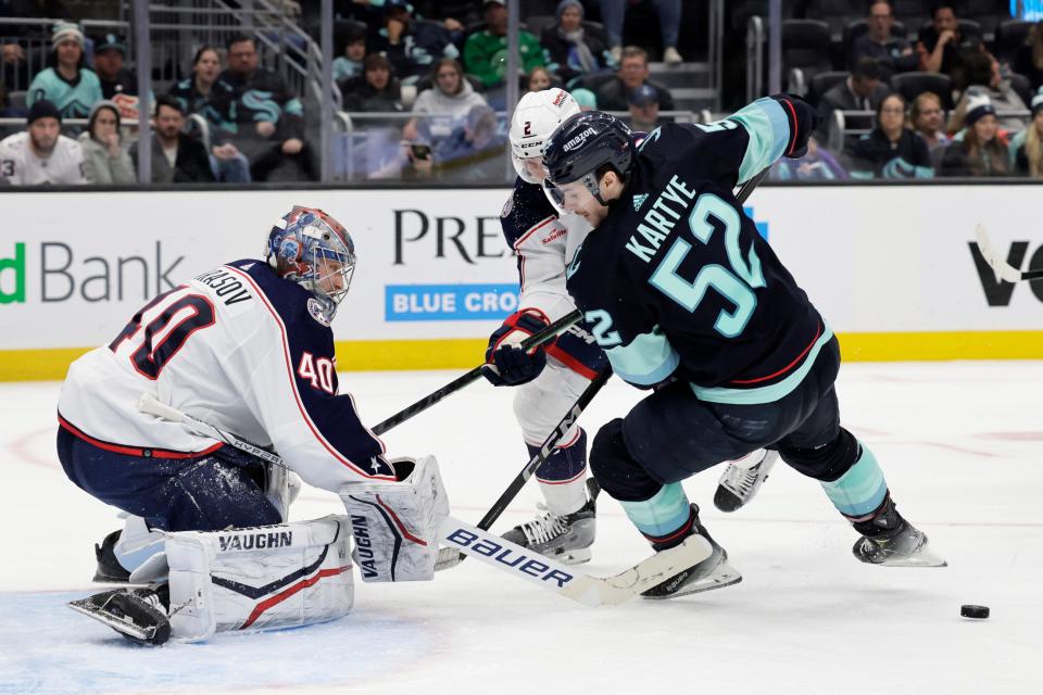 Seattle Kraken left wing Tye Kartye (52) battles with Columbus Blue Jackets defenseman Andrew Peeke (2), behind, and goaltender Daniil Tarasov (40) during the third period of an NHL hockey game, Sunday, Jan. 28, 2024, in Seattle. The Kraken won 4-2. (AP Photo/John Froschauer)