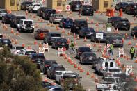 FILE - In this July 14, 2020, file photo, people wait in line for coronavirus testing at Dodger Stadium in Los Angeles. The pandemic began with devastation in the New York City area, and was followed by a summertime crisis in the Sun Belt. But it is now striking cities with much smaller populations, often in conservative corners of America where anti-mask sentiment runs high, creating problems at hospitals and schools in the Midwest and West. (AP Photo/Mark J. Terrill, File)