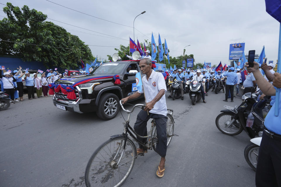 An elderly man rides a bicycle as he participates in a procession to mark the end of an election campaign of the Cambodian People's Party in Phnom Penh, Cambodia, Friday, July 21, 2023. The three-week official campaigning period ended Friday for the July 23 general election. Eighteen parties are contesting the polls, but Prime Minister Hun Sen's ruling Cambodian People's Party is virtually guaranteed a landslide victory. (AP Photo/Heng Sinith)