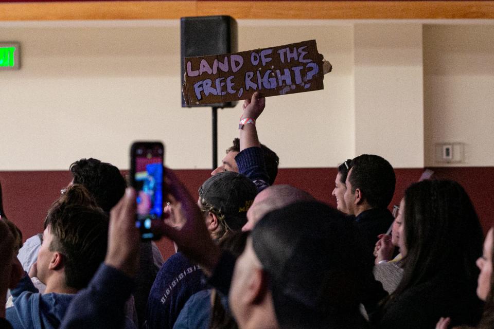 An attendee holds a protest sign inside the Matt Walsh talk on April 4, 2023.