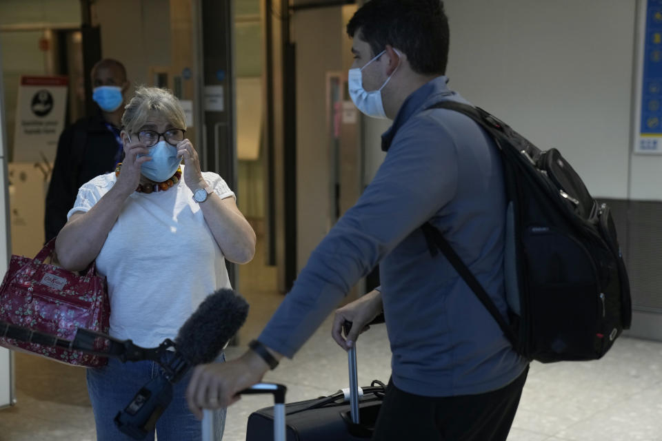 Whilst giving a television interview, Karen Tyler wipes tears of happiness away after greeting her son Jonathan, who she's not seen for over a year and a half, as he arrives on a flight from Houston, Texas, in the U.S., at Terminal 5 of Heathrow Airport in London, Monday, Aug. 2, 2021. Travelers fully vaccinated against coronavirus from the United States and much of Europe were able to enter Britain without quarantining starting today, a move welcomed by Britain's ailing travel industry. (AP Photo/Matt Dunham)