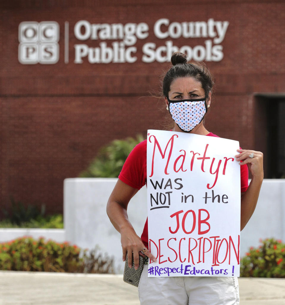 Rachel Bardes holds a sign in front of the Orange County Public Schools headquarters in Orlando, Fla., on July 7, 2020, as teachers protest a mandate that all public schools open in August despite the spike in coronavirus cases in Florida. | Joe Burbank—Orlando Sentinel/AP