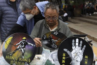 Hong Kong men prepare protest themed clocks made from vinyl records ahead of a rally demanding electoral democracy and call for boycott of the Chinese Communist Party and all businesses seen to support it in Hong Kong, Sunday, Jan. 19, 2020. Hong Kong has been wracked by often violent anti-government protests since June, although they have diminished considerably in scale following a landslide win by opposition candidates in races for district councilors late last year. (AP Photo/Ng Han Guan)