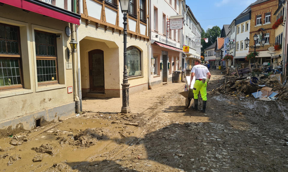 A man uses a wheelbarrow to move debris through the streets of the flood hit town of Ahrweiler, Germany, on Friday, July 23, 2021. With the death toll and economic damage from last week’s floods in Germany continuing to rise, questions have been raised about why systems designed to warn people of the impending disaster didn’t work. (AP Photo/Frank Jordans)