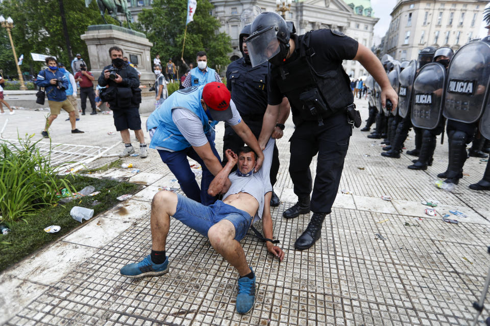 Police detain a soccer outside the presidential palace where Diego Maradona is lying in Buenos Aires, Argentina, Thursday, Nov. 26, 2020. The Argentine soccer great who led his country to the 1986 World Cup title died of a heart attack at his home Wednesday at the age of 60. (AP Photo/Natacha Pisarenko)