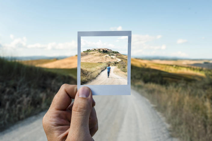 Personal perspective of polaroid picture overlapping a country road in Tuscany