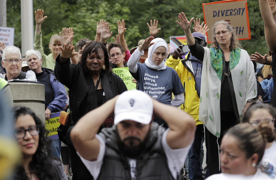 In this photo taken Wednesday, July 17, 2019, Jose Robles, front center, rests with his hands behind his head as supporters hold their arms toward him during a blessing before he presented himself to U.S. Immigration and Customs Enforcement officials in Tukwila, Wash. The prospect of nationwide immigration raids has provided evidence that legions of pastors, rabbis and their congregations stand ready to help vulnerable immigrants with offers of sanctuary and other services. (AP Photo/Elaine Thompson)
