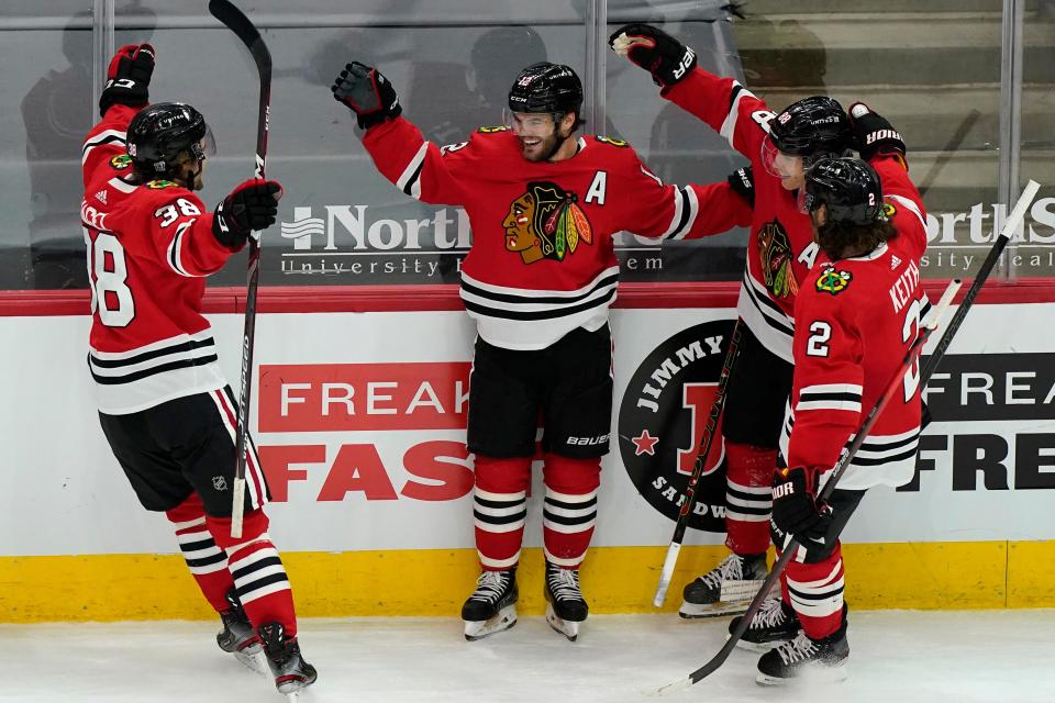 Chicago Blackhawks' Alex DeBrincat, second from left, celebrates with teammates Brandon Hagel, left, Duncan Keith, right, and Patrick Kane after scoring the winning goal against the Columbus Blue Jackets during the overtime period of an NHL hockey game in Chicago, Saturday, Feb. 13, 2021. (AP Photo/Nam Y. Huh)