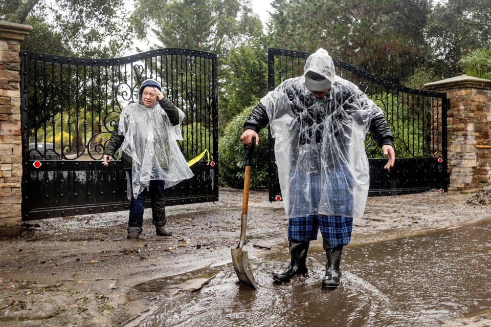 Alex, left, and Aron Moreno work to divert water from their property as heavy rains fall in Salinas, Calif., on Wednesday, Jan. 27, 2021. The couple lives below hillsides scorched in last year's River Fire where water and mud is now flowing downhill from burned land. (AP Photo/Noah Berger)