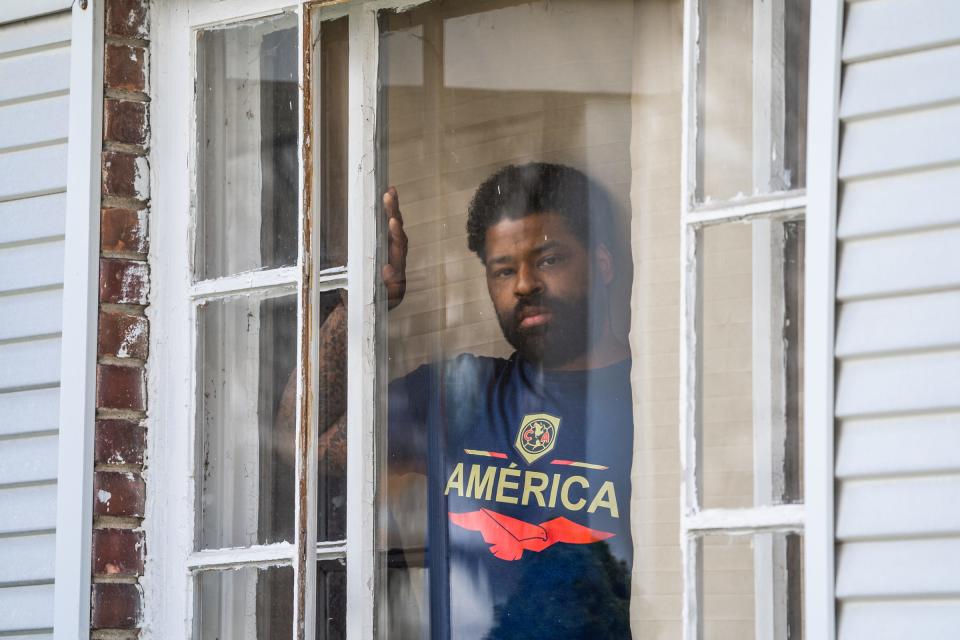 Keith Gambrell, of Detroit, is seen in a window of his house while in quarantine with COVID-19 symptoms on Friday, April 10, 2020. Gambrell lost his grandfather and stepfather to COVID-19. His mother was admitted to Henry Ford Hospital and needed a ventilator.