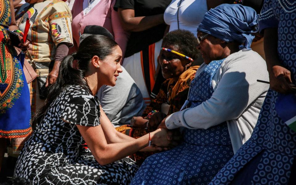 Meghan, Duchess of Sussex speaks with a woman during a visit with her husband to "Justice desk", an NGO in the township of Nyanga in Cape Town, as they begin their tour of the region on September 23, 2019 - Betram MALGAS / POOL