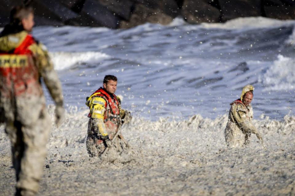 Rescue workers seen wading through rough foamy waters.