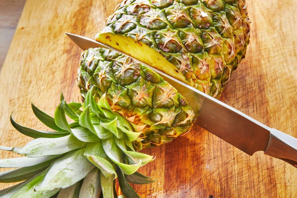 a knife slicing into a whole pineapple