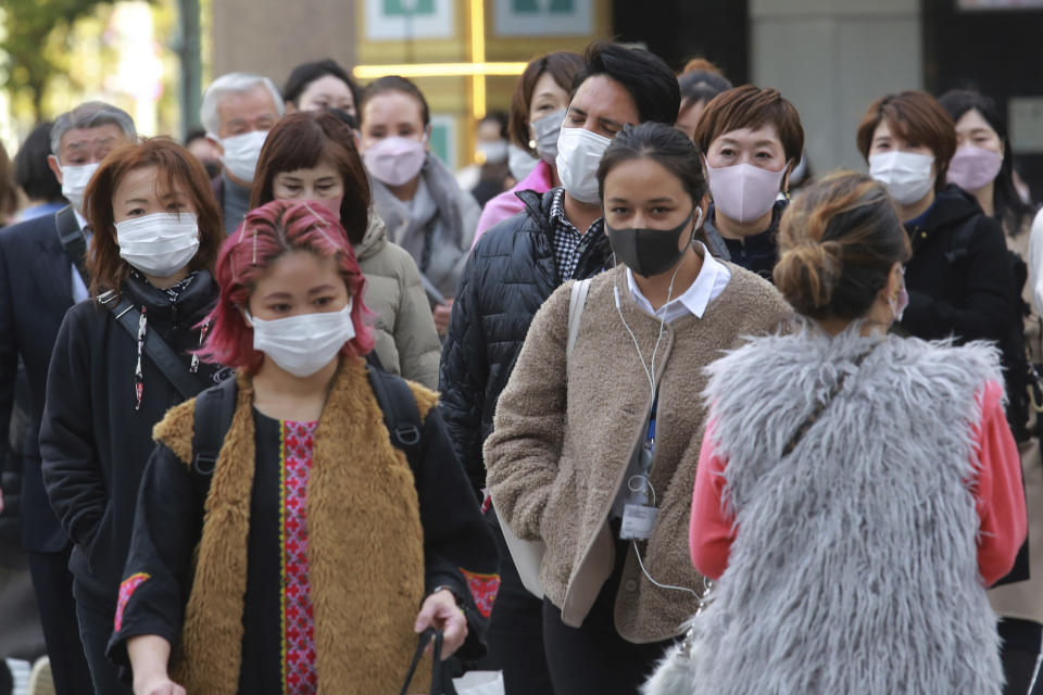 People wearing face masks to protect against the spread of the coronavirus walk along a street in Tokyo, Monday, Nov. 29, 2021. (AP Photo/Koji Sasahara)