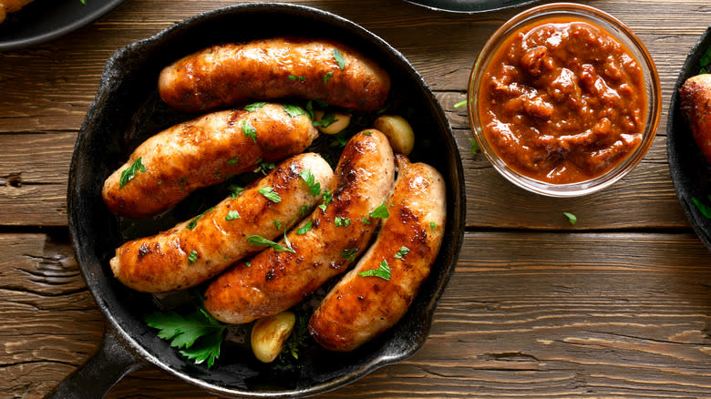 Sausages in cast iron pan with herbs and garlic