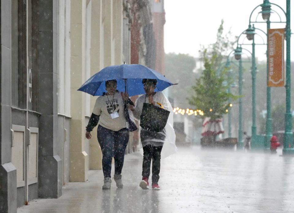 Tyrianna Wright (left) and Cheyenne Shelby share an umbrella while walking through the rain in the Third Ward along North Broadway Street in Milwaukee on Monday, May 20, 2024.