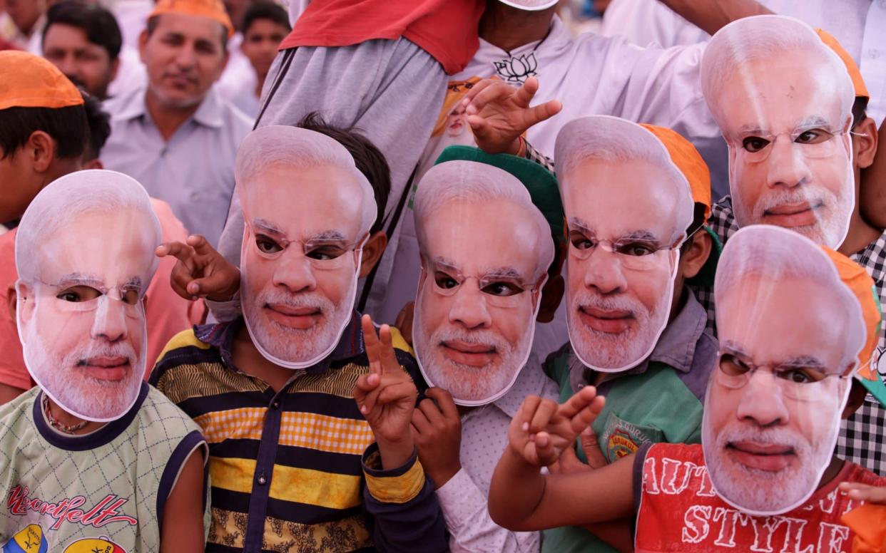 Supporters of Narendra Modi wear masks as masks  as they attend a Bharatiya Janata Party election campaign rally - REX
