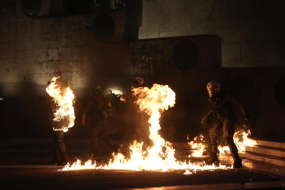 A masked demonstrator throws a petrol bomb to riot police in Athens