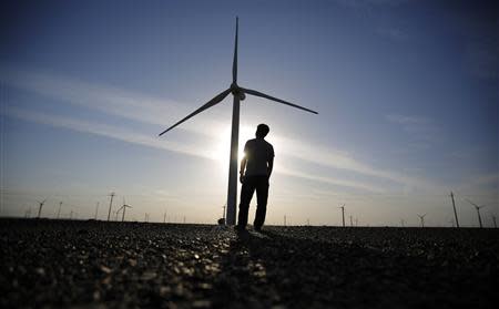 A worker stands as he looks at a wind turbine used to generate electricity, at a wind farm in Guazhou, 950km (590 miles) northwest of Lanzhou, Gansu Province September 15, 2013. REUTERS/Carlos Barria