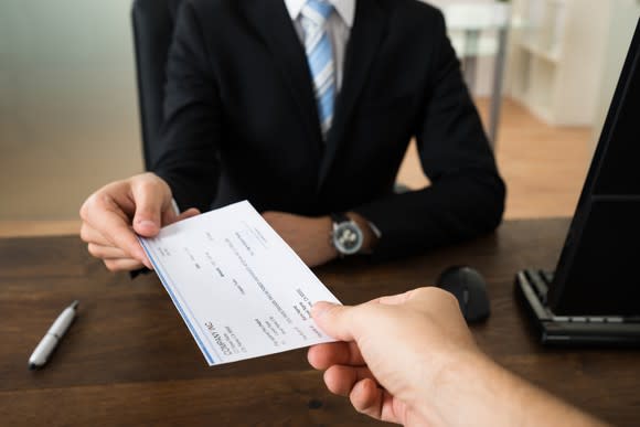 Businessperson handing someone a check.