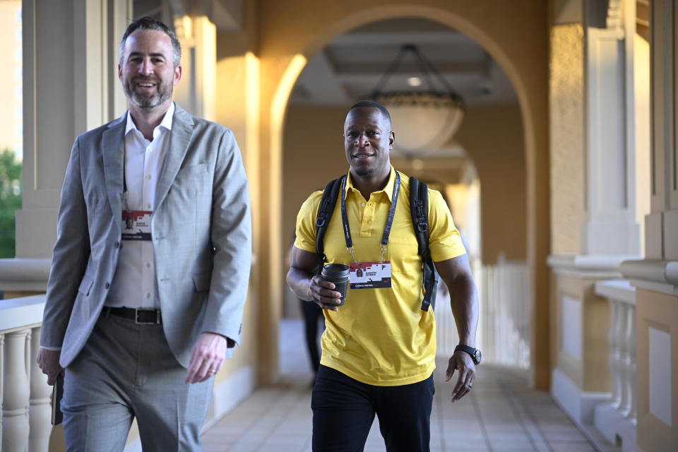 Atlanta Falcons head coach Raheem Morris, right, walks to an NFC coaches availability at the NFL football owners meetings, Tuesday, March 26, 2024, in Orlando, Fla. (AP Photo/Phelan M. Ebenhack)