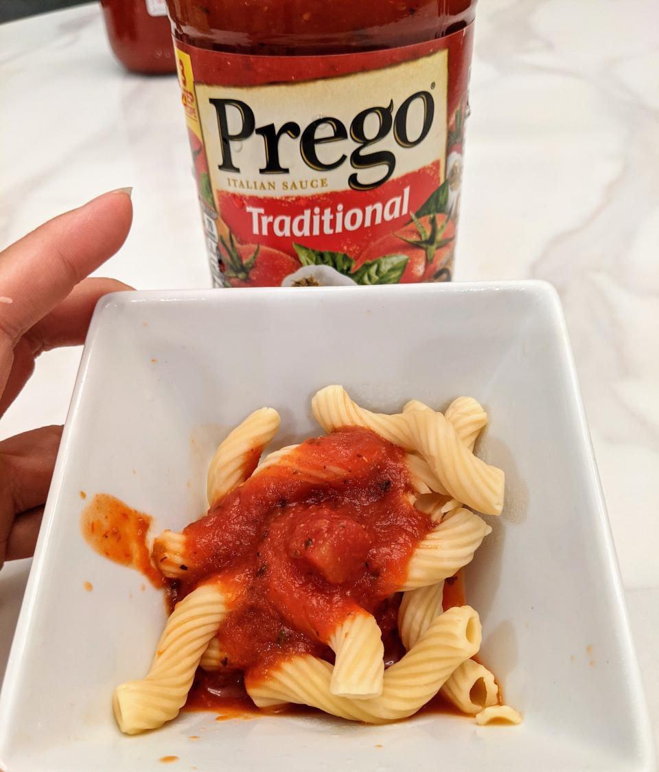 Jar of prego red sauce behind a small white bowl of pasta