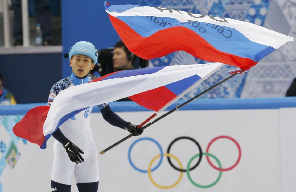 Victor An of Russia waves flags after he won the men's 1,000 metres short track speed skating final event at the Iceberg Skating Palace during the 2014 Sochi Winter Olympics February 15, 2014. REUTERS/Alexander Demianchuk