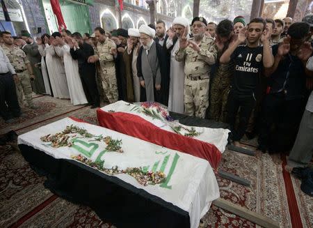 Mourners pray in front of the coffins of Shi'ite volunteers, who had joined the Iraqi Army and were killed during clashes with militants of the Islamic State, formerly known as the Islamic State of Iraq and the Levant (ISIL), during a funeral in Kerbala, southwest of Baghdad, July 12, 2014. REUTERS/Mushtaq Muhammed