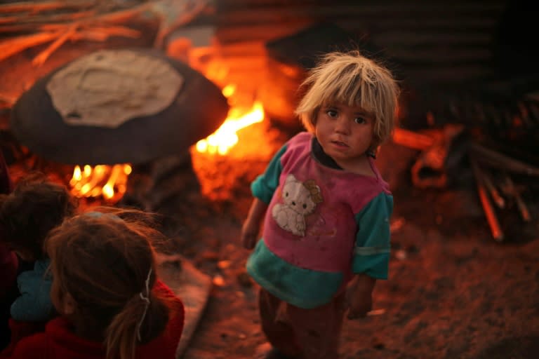 A Syrian child stands next to a bread-baking pit at the Ash'ari camp for the displaced in rebel-held Eastern Ghouta near Damascus on October 25, 2017