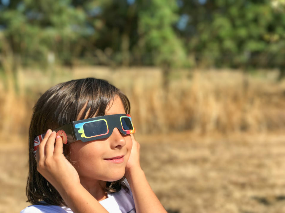 A young girl looking at the sun during a solar eclipse on a country park, family outdoor activity.