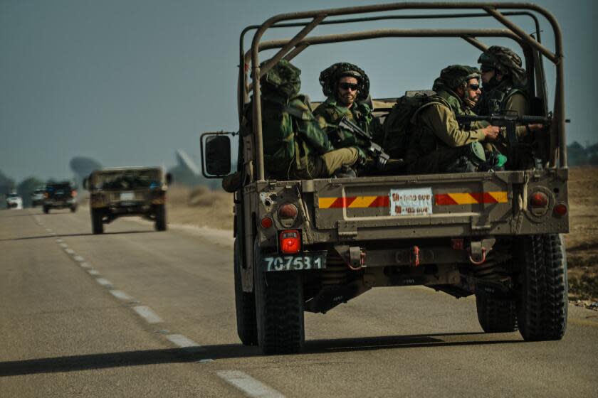 RE'IM, ISRAEL -- OCTOBER 10, 2023: Israeli soldiers ride on a transport vehicle near Re'im, Israel, Tuesday, Oct. 10, 2023. Last week, Israel was caught by surprise after Hamas cross Israeli border and launched a multi-pronged attack which led to the deadliest bout of violence to hit Israel in 50 years that has taken more than a thousand lives on both sides. (MARCUS YAM / LOS ANGELES TIMES)