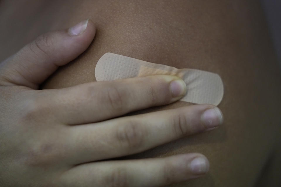 Eduarda, from Brazil, presses a bandaid on her shoulder after receiving the Pfizer coronavirus vaccine at a vaccination center in Lisbon, Tuesday, Sept. 21, 2021. As Portugal nears its goal of fully vaccinating 85% of the population against COVID-19 in nine months, other countries want to know how it was able to accomplish the feat. A lot of the credit is going to Rear Adm. Henrique Gouveia e Melo. (AP Photo/Armando Franca)