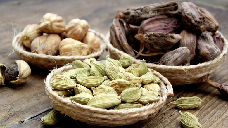 white, black, and green cardamom pods in woven bowls