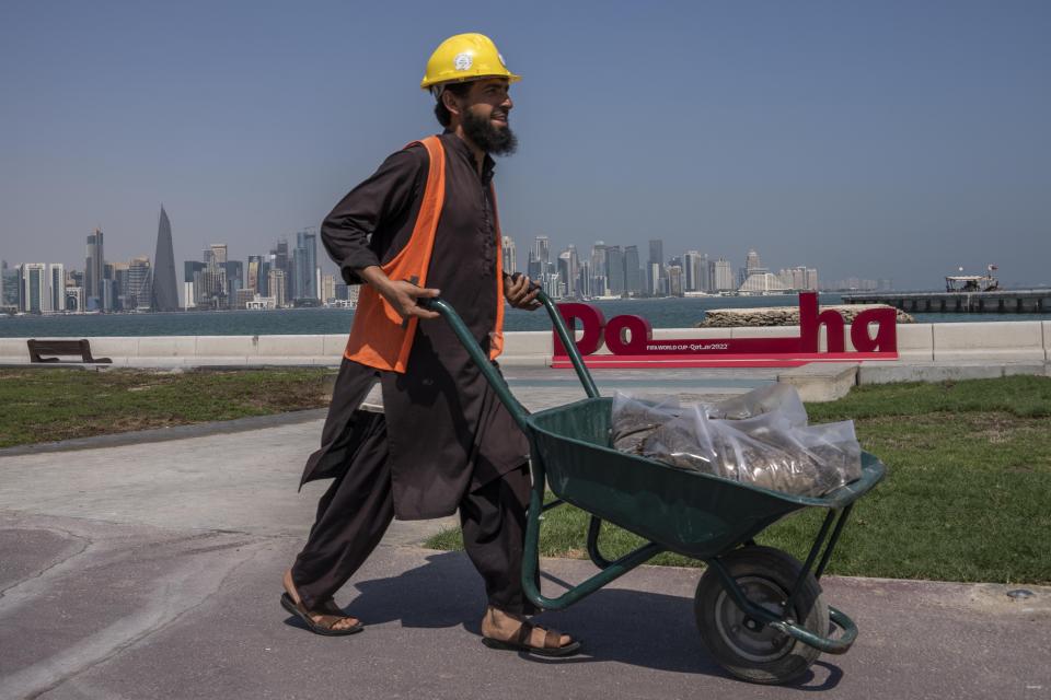 A Pakistani migrant laborer works on the corniche, overlooking the skyline of Doha, Qatar, Wednesday, Oct. 19, 2022. One of the world’s biggest sporting events has thrown an uncomfortable spotlight on Qatar’s labor system, which links workers’ visas to employers and keeps wages low for workers toiling in difficult conditions. (AP Photo/Nariman El-Mofty)