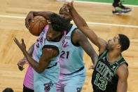 Miami Heat's Jimmy Butler, left, grabs a rebound as Boston Celtics' Tristan Thompson, right, vies for the ball while Heat's Dewayne Dedmon, behind, looks on in the first half of a basketball game, Sunday, May 9, 2021, in Boston. (AP Photo/Steven Senne)