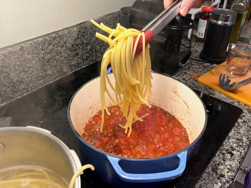 Adding the pasta to the sauce for Ina Garten's weeknight pasta