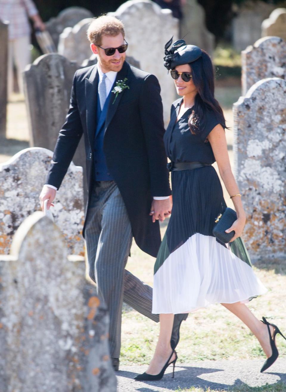 <p>Attending the wedding of friends Charlie van Straubenzee and Daisy Jenks' wedding, Markle wore a sophisticated Club Monaco black dress with green and pink in the pleated skirt teamed with a black Philip Treacy fascinator with <a href="https://www.farfetch.com/uk/shopping/women/aquazzura-deneuve-105-pumps-item-13085027.aspx?storeid=9774&size=24&pid=googleadwords_int&af_channel=Search&c=629762120&af_c_id=629762120&af_keywords=pla-383089413039&af_adset_id=52804059504&af_ad_id=218064673083&is_retargeting=true&shopping=yes&gclid=EAIaIQobChMI2bjB_KjY3AIVVwQqCh3fnACzEAQYBSABEgLPY_D_BwE" rel="nofollow noopener" target="_blank" data-ylk="slk:Aquazzura;elm:context_link;itc:0;sec:content-canvas" class="link ">Aquazzura</a> heels.</p><p>She accessorised the look with a pair of <a href="https://uk.lindafarrow.com/linda-farrow-512-c3-oval-sunglasses.html" rel="nofollow noopener" target="_blank" data-ylk="slk:Linda Farrow oval sunglasses;elm:context_link;itc:0;sec:content-canvas" class="link ">Linda Farrow oval sunglasses</a> and a <a href="https://modesens.com/gb/en/product/KAYU-ANNA-STRAW-CLUTCH-NATURAL-8321604/?refinfo=gSH_ggffb8321604&gclid=EAIaIQobChMIwObf76jY3AIVkAMqCh1AewaaEAQYBiABEgLQz_D_BwE" rel="nofollow noopener" target="_blank" data-ylk="slk:Kayu Anna straw clutch bag;elm:context_link;itc:0;sec:content-canvas" class="link ">Kayu Anna straw clutch bag</a>, August 2018. </p>