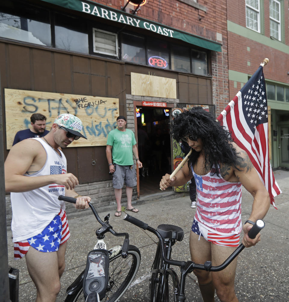 Jeff Egyp, right, and Brandon Fresin, left, park there bikes outside the Barbary Coast bar in downtown Wilmington, N.C., as the Florence threatens the coast Thursday, Sept. 13, 2018. (AP Photo/Chuck Burton)