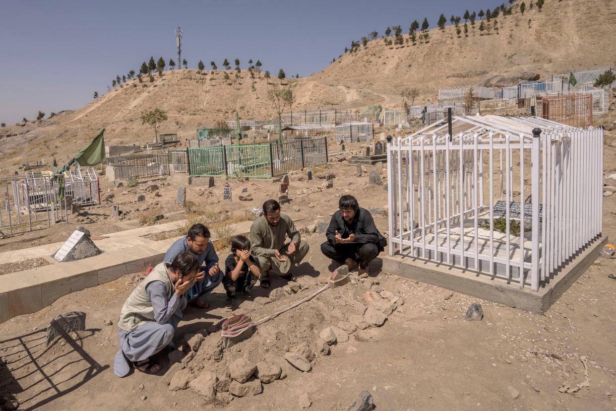 In this photo taken Monday, the Ahmadi family pray at the cemetery next to family graves of family members killed by a U.S. drone strike, in Kabul.