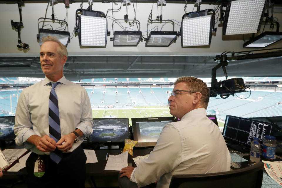 In this Friday, Aug. 23, 2019, photo, Fox Sports play-by-play announcer Joe Buck, left, and analyst Troy Aikman, right, work in the broadcast booth before a preseason NFL football game between the Miami Dolphins and Jacksonville Jaguars, in Miami Gardens, Fla. The exhibition game served as a dress rehearsal for the Fox Sports crew for the upcoming Super Bowl to be hosted by Miami in 2020. (AP Photo/Lynne Sladky)