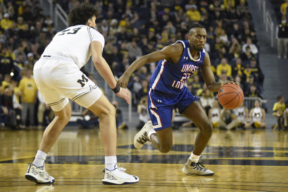 UMass-Lowell guard Christian Lutete, right, dribbles around Michigan forward Brandon Johns Jr. during the first half of an NCAA college basketball game, Sunday, Dec. 29, 2019, in Ann Arbor, Mich. (AP Photo/Jose Juarez)