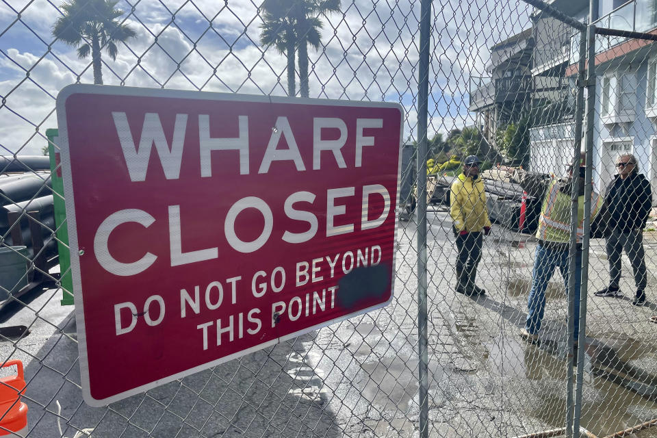 People work behind a closed area of the Capitola Wharf, Monday, Jan. 22, 2024, in Capitola, Calif. Rising seas, frequent storms take toll on California's iconic piers, threatening beach landmarks. (AP Photo/Haven Daley)