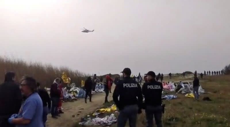 Una captura de pantalla tomada de un video muestra a policías parados en la playa donde se encontraron los cuerpos de los que se cree que eran refugiados después de un naufragio, en Cutro, la costa este de la región italiana de Calabria, Italia