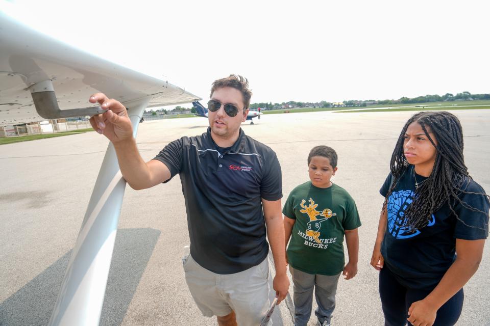 Flight instructor Alec Bouchard, leads Brayden Williams and Ella Robinson around a Cessna Skyhawk for an inspection on July 15, 2023, at Timmerman Airport in Milwaukee.
