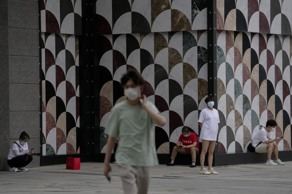 Residents wearing face masks wait outside a shopping mall after authorities allowed malls outside the COVID-19 locked down and controlled zones to open in Beijing, Sunday, May 29, 2022. (AP Photo/Andy Wong)