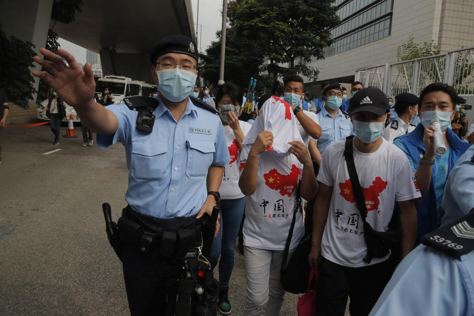 Pro-China activists are escorted by police officers as they argue with pro-democracy protesters outside a court during a protest in Hong Kong, Thursday, Aug. 27, 2020. Hong Kong police arrested 16 people, including two opposition lawmakers, on Wednesday on charges related to anti-government protests last year. (AP Photo/Kin Cheung)