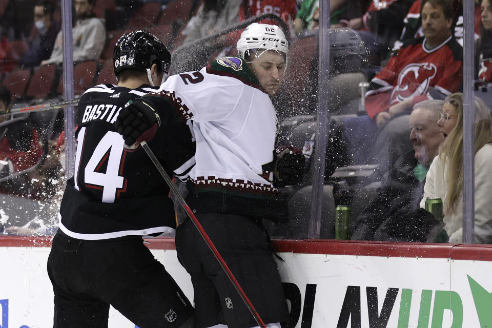 New Jersey Devils right wing Nathan Bastian (14) checks Arizona Coyotes defenseman Janis Moser (62) during the first period of an NHL hockey game Wednesday, Jan. 19, 2022, in Newark, N.J. (AP Photo/Adam Hunger)